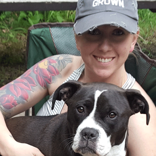 Natalie, professional Groomer for The Chase dog spa, snuggles a boxer mix.